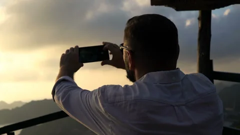 Man taking cellphone photo of Ha Long Bay in Vietnam during sunset Stock Footage 163336844