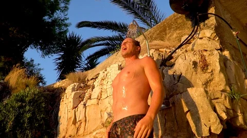 A man taking a cold shower under at a beautiful rocky background Stock Footage 114863940
