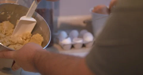 Man taking Cookie Dough out of a Mixing Bowl and Placing it on Parchment Paper Stock Footage 101050816