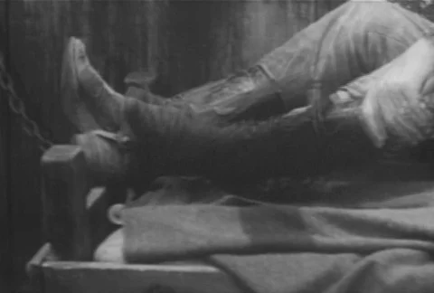 Man taking off cowboy boot and removing leg iron, 1930s Video stock 95997056