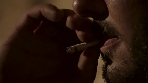 Man taking drag of cigarette, orange glow 스톡 동영상 152182618
