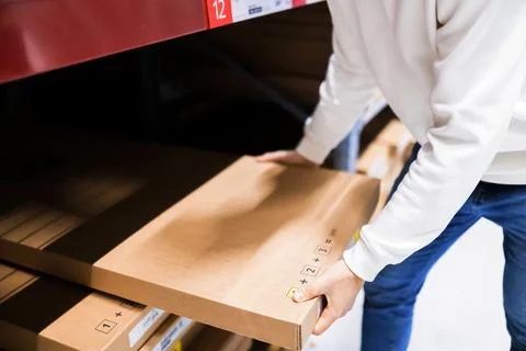 Man taking a flat cardboard box from a shelf in a self-service warehouse fu.. Stock Photos