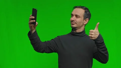 A man taking a funny selfie on his phone, posing and making a victory gesture on Stock Footage 169107784