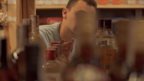 Man is taking gin bottle in the shop close up Customer is choosing drink in Stock Footage 99385585