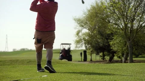 Man taking golf swing from tee box on par 3 hole Stock Footage 189290306
