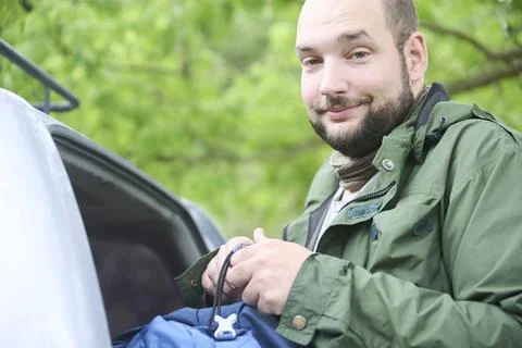 Man taking his backpack out of the trunk of the car. Stock Photos