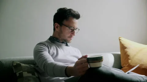 Man taking off his glasses and looking at tea cup after taking a sip Stock Footage 130637012