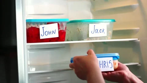 Man taking his lunchbox from fridge. Meal containers labeled with employee Stock Footage 311779792