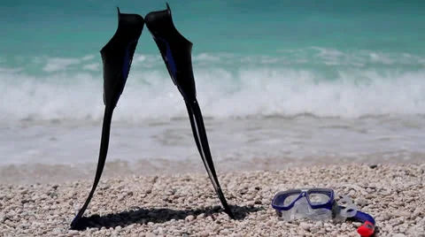 Man taking his scuba diving fins, snorkel and a mask from a shingle beach Stock Footage 25991653