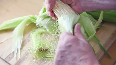 Man taking husk off corn Stock Footage 76088438