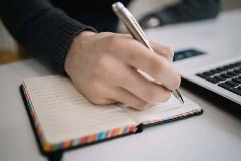 Man taking notes and writing in notepad with pen Stock Photos