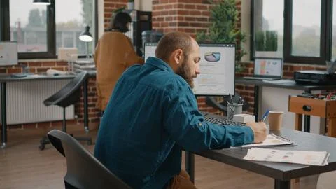 Man taking notes on charts papers and looking at computer 스톡 사진