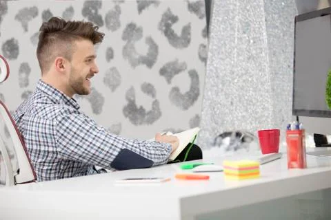 Man taking notes down from his new laptop computer at work in the morning office 스톡 사진