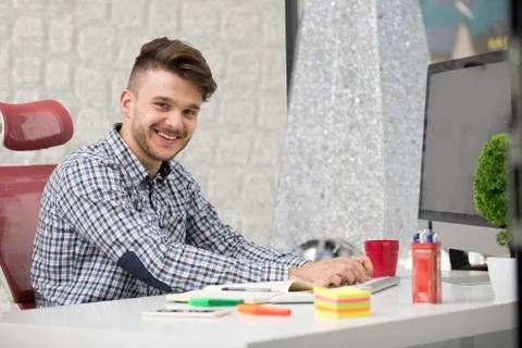 Man taking notes down from his new laptop computer at work in the morning office Stock Photos