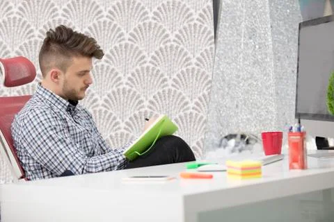 Man taking notes down from his new laptop computer at work in the morning office Stock Photos