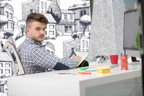 Man taking notes down from his new laptop computer at work in the morning office Stock Photos
