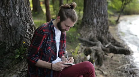 Man taking notes in a notebook sitting on the shore Stock Footage 65220816