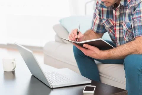 A man taking notes notebook sitting on a sofa 스톡 사진