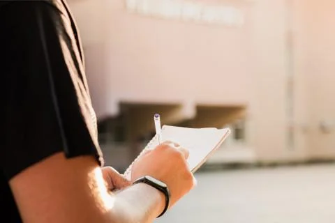 Man taking notes outside an educational facility.  Stock Photos