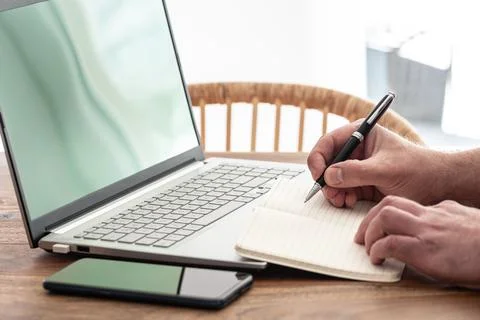 Man taking notes on paper while using laptop computer Stock Photos