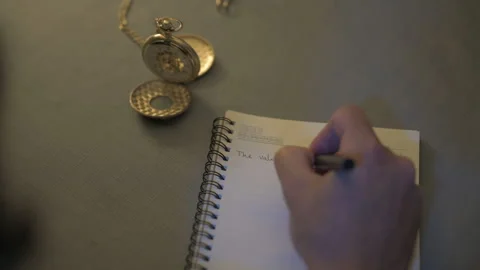 Man taking notes on a piece of paper near gold watch close up Stock Footage 246259572