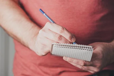 Man taking notes on small spiral notepad using a pencil Stock Photos