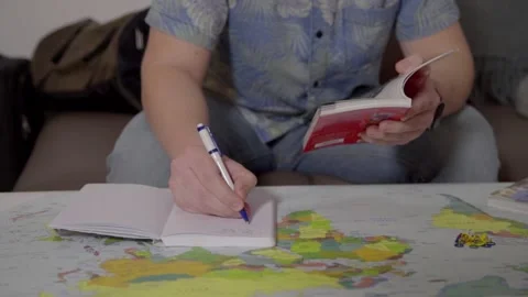 Man taking notes from a turist guide on a world map Video stock 135333562
