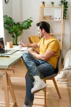 Man taking notes while watching online classes. Stock Photos