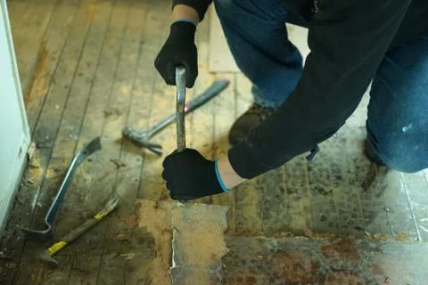 A man taking off old floor in kitchen. Stock Photos