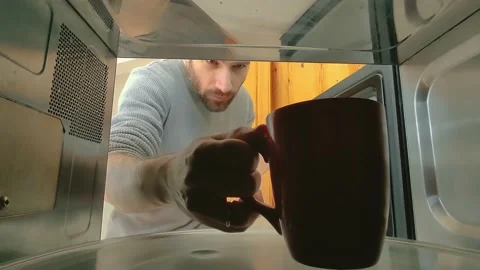 A man taking out a cup of tea or coffee heated up in a microwave Stock Footage 237736432