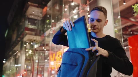 A man taking out laptop in a case in the city at night Stock Footage 253195395