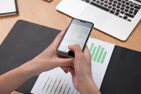 Man taking photo of document using scanning app on smartphone at desk in of.. Stock Photos