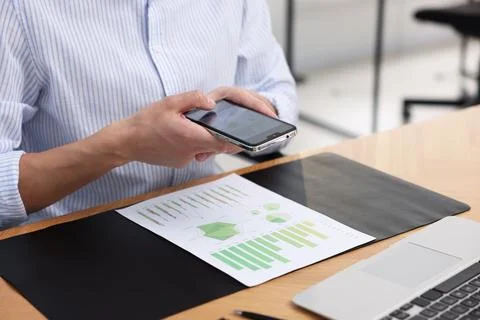 Man taking photo of document using scanning app on smartphone at desk in of.. Stock Photos