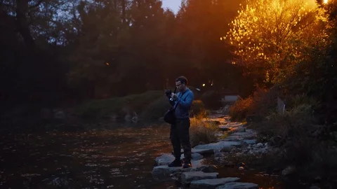 Man is taking a photo on his camera in a dark mystic garden with lights. Video stock 120477353