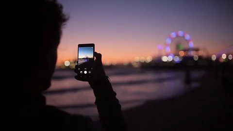 A man taking photo of a young beautiful posing woman on the beach on the sunset Stock Footage