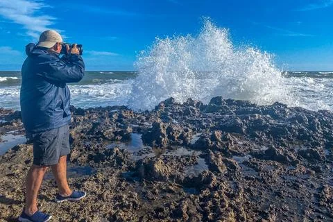 Man taking photos with a camera while standing on the rocky coast while the Stock Photos