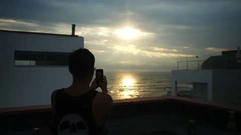 A man taking photos with his cell phone to a beautiful view of the sun half Vidéo 178471649