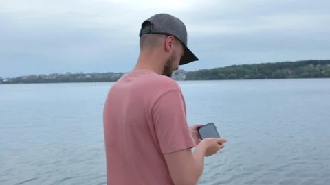 Man taking photos while standing near lake in slow motion Stock Footage 91726206