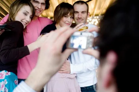 Man taking picture of 2 smiling couples Stock Photos