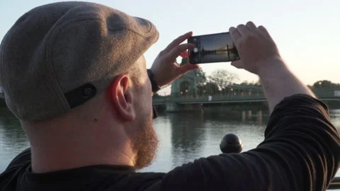 Man taking a picture of Hammersmith Bridge during sunset Stock Footage 166527468