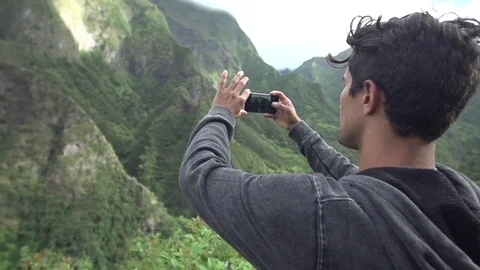 Man Taking Picture of Mountains on iPhone Clifftop Adventure Stock Footage 82352932