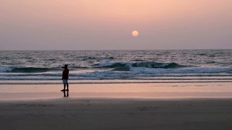 A man taking picture on the phone of dramatic sunset on the beach In India Stock Footage 113567009