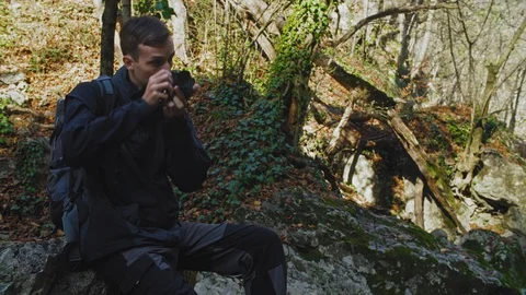 Man taking a picture of a small waterfall in the forest. 4k Stock Footage 102340704