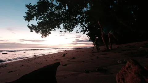 Man Taking Picture of Sunrise Using Professional Camera and Tripod at Beach Stock Footage 202491985
