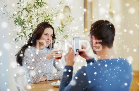Man taking picture of woman by smartphone at cafe Stock Photos