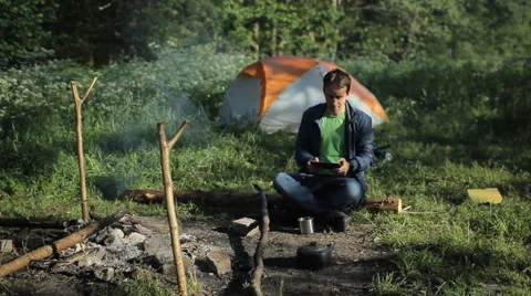 A man taking pictures a fire on the tablet. Against the background is a tent in Stock Footage 64328250