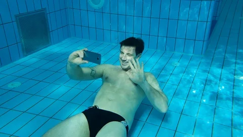 A man taking a selfie with his mobile phone under water in a swimming pool Stock Footage 103355022