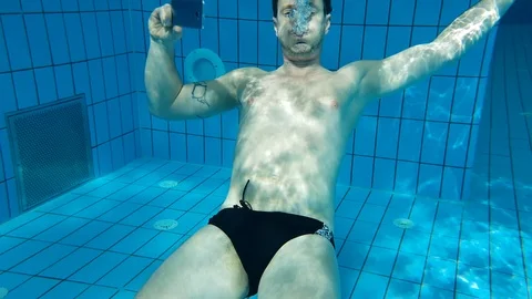 A man taking a selfie with his mobile phone under water in a swimming pool 库存影片 103355041