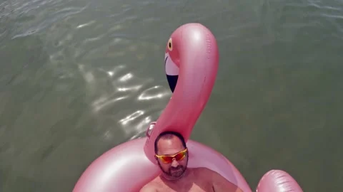 Man taking selfie with long stick while relaxing on inflatable Stock Footage 278853102