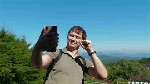 Man taking selfie in nature, smiling and showing peace sign, enjoying Видео 280021578